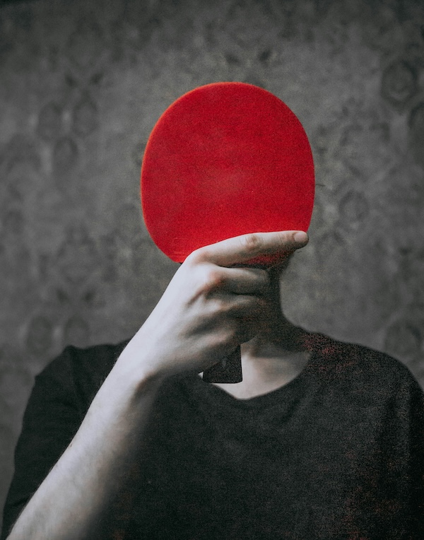 Person hiding behind a ping-pong paddle